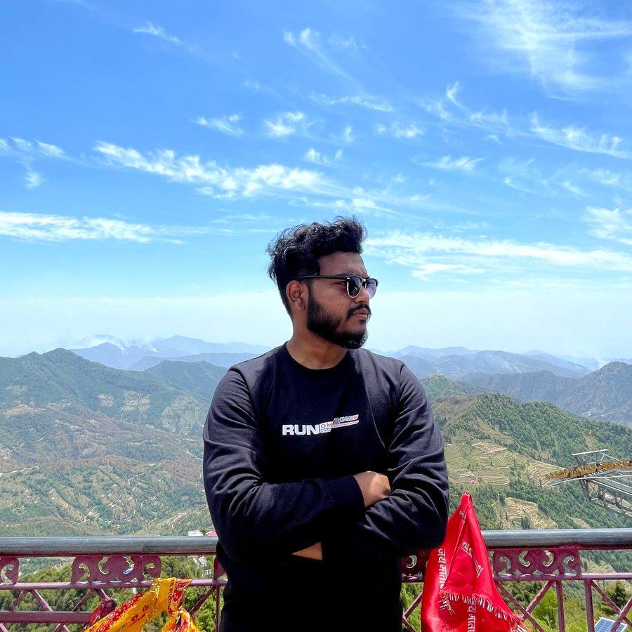 Jai on a hilltop viewpoint, arms crossed