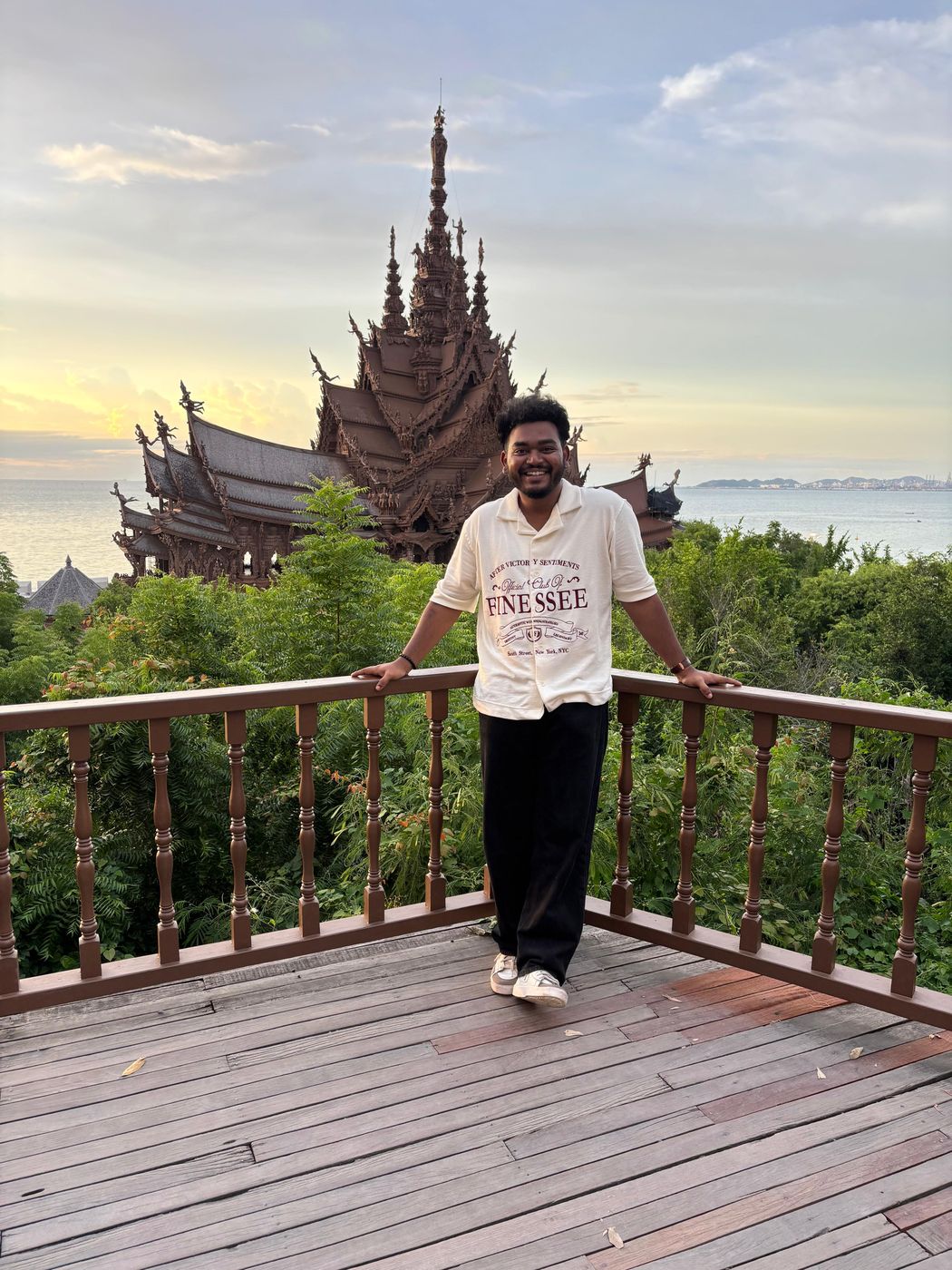 Jai on a wooden deck in front of a carved temple by the sea
